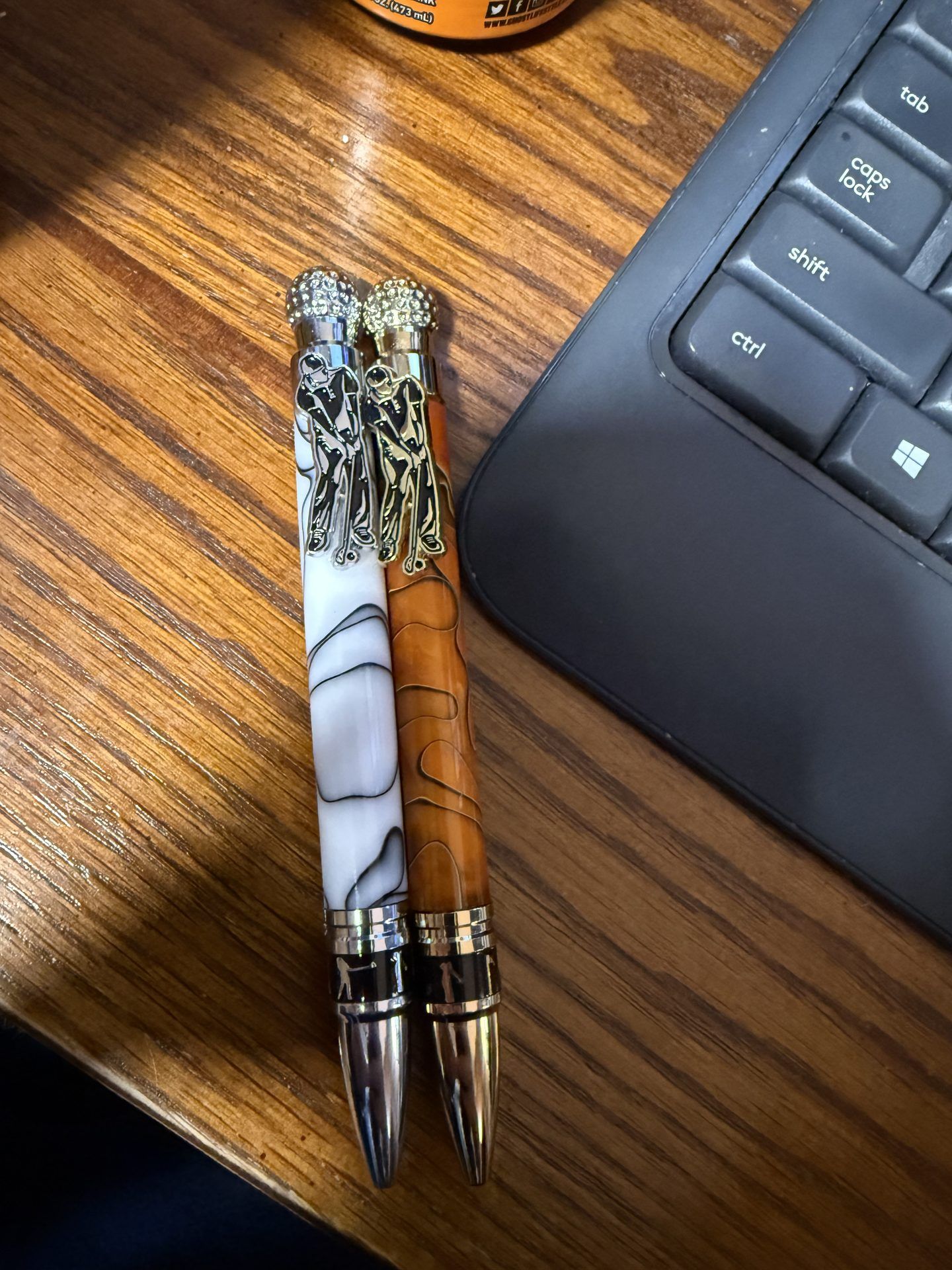 Two handcrafted pens — one turned wood, one marbled acrylic with decorative clips