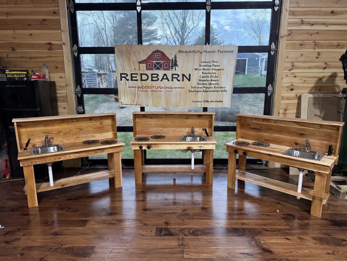 Three outdoor kitchen stations lined up in the Redbarn workshop with the Redbarn Wood Turning banner