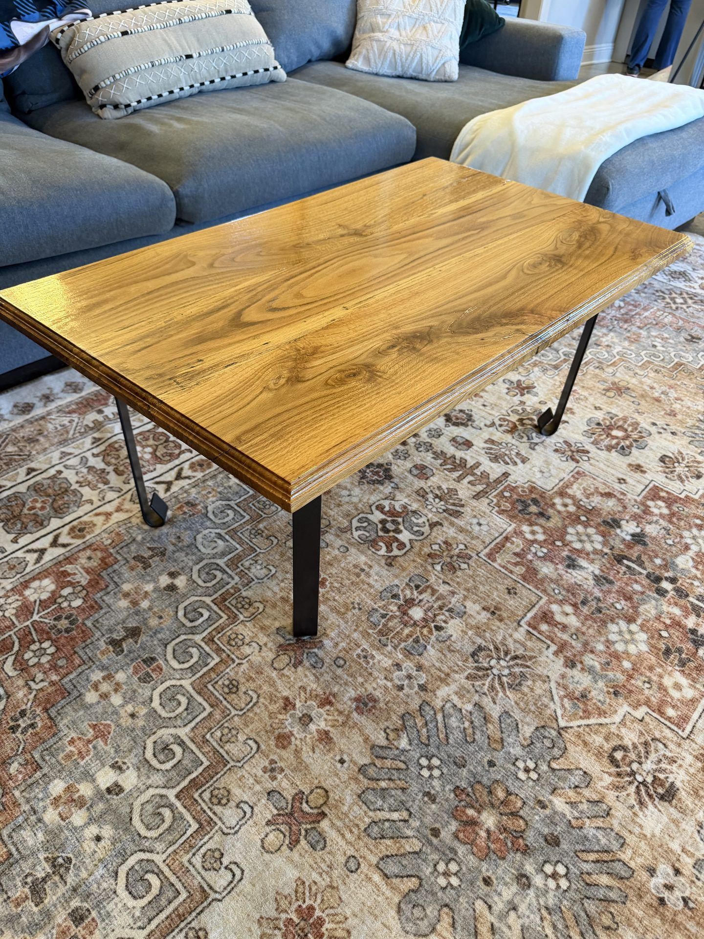 Warm-toned wood side table with black metal legs in a living room
